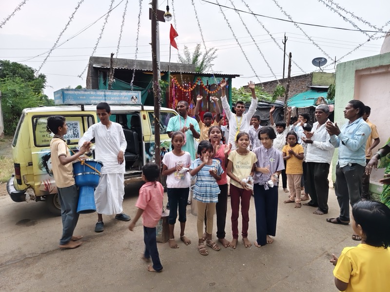A devotee handing out packets of prasadam to children gathered by the roadside